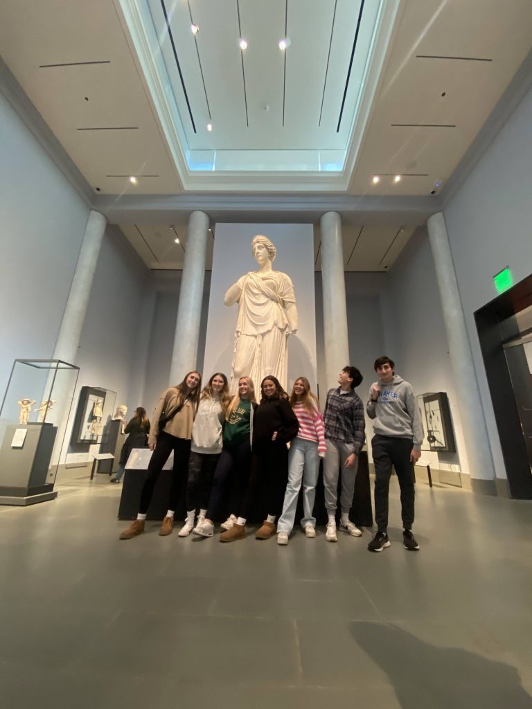 An image of a smaller group of students posing in front of a statue at the Museum of Modern Arts.