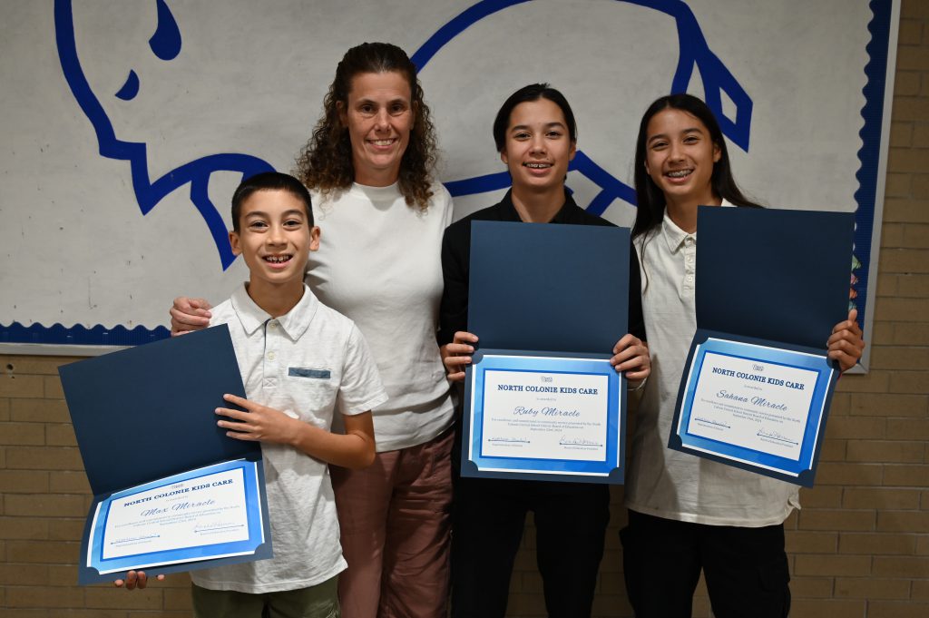 An image of the three Miracle siblings posing with teacher Paige Rossi.