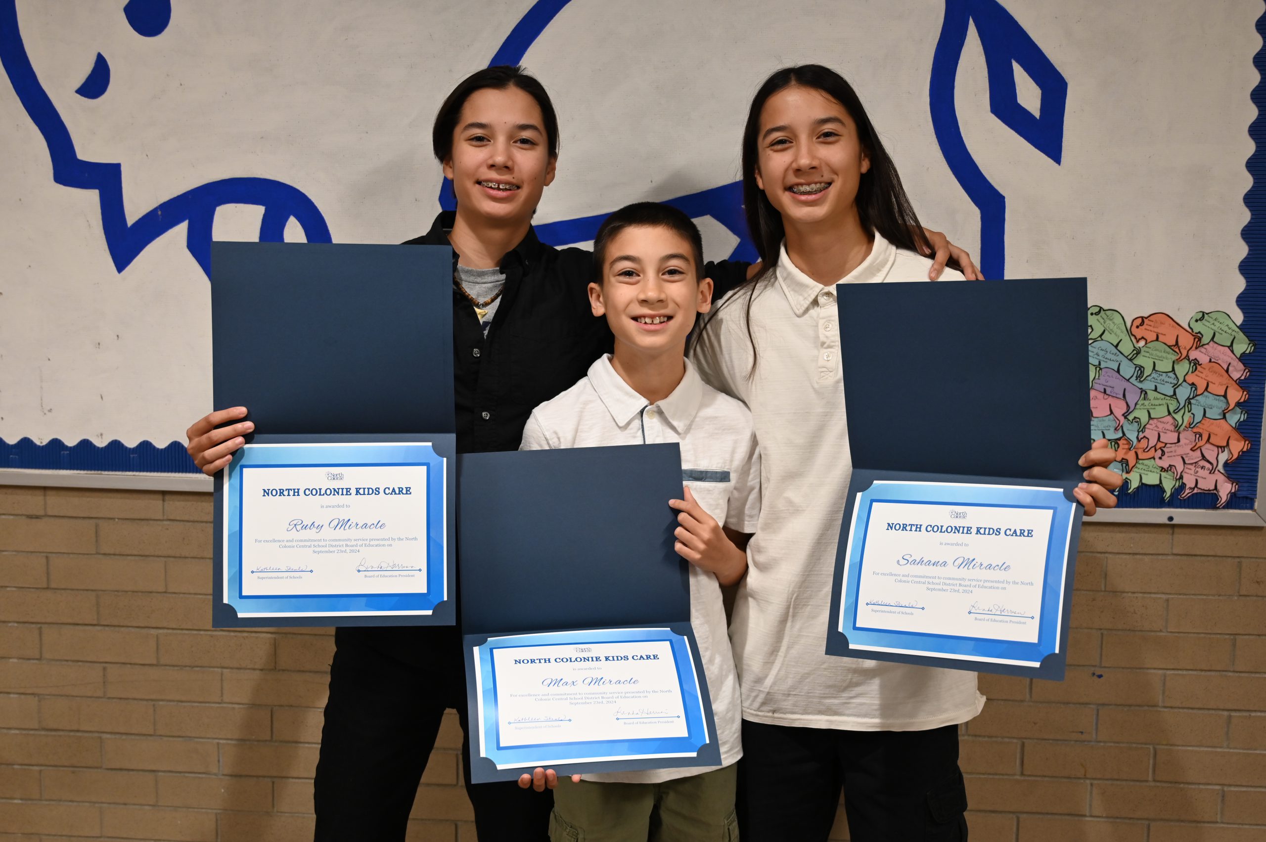 An image of the Miracle siblings holding their certificates for September Kids Care.