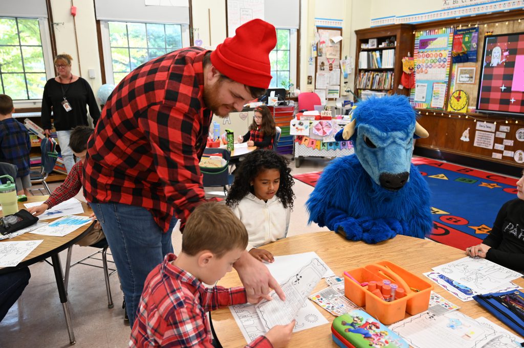 An image of Paul Bunyan and Babe the Ox with students at a table.