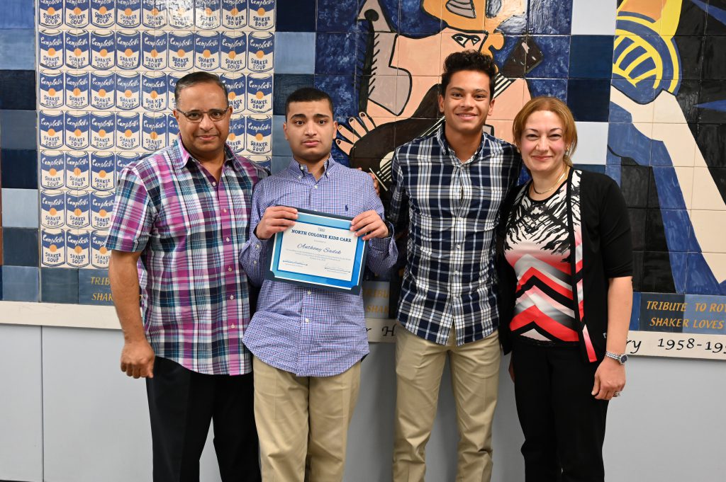 An image of a student and his family as he holds a certificate.