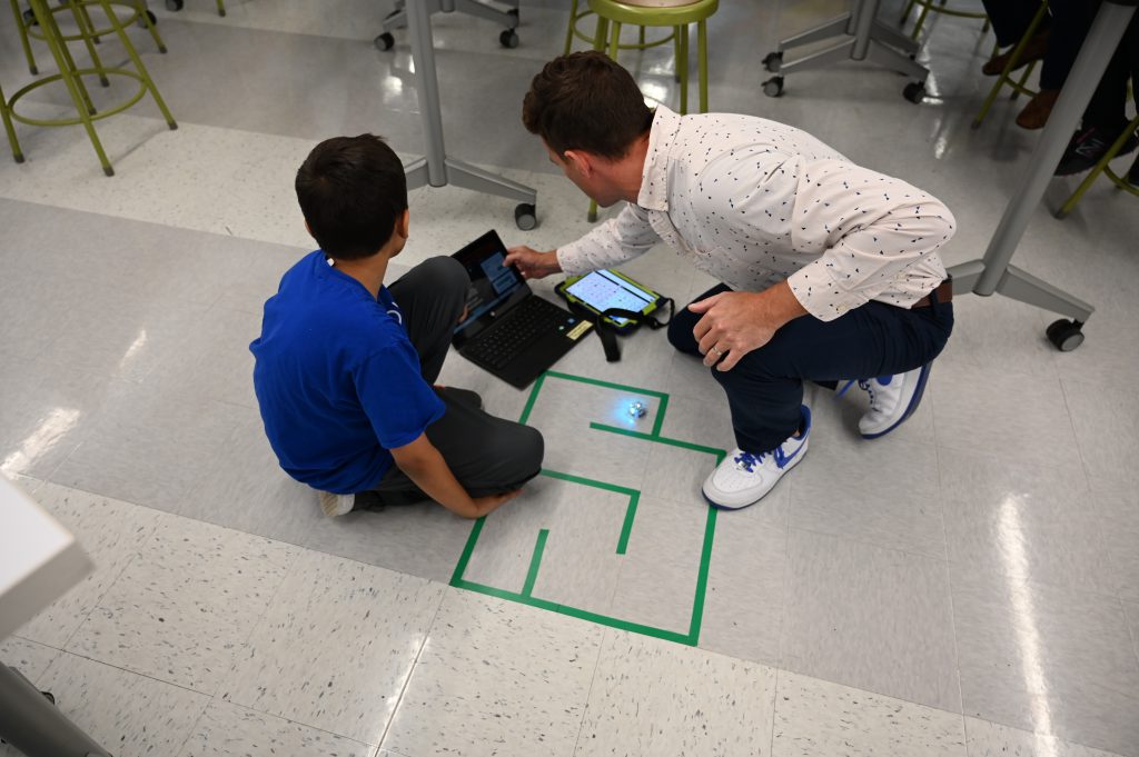 An image of a student and teacher working on a project on the floor.