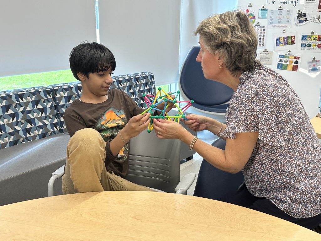 An image of a teacher and student holding an object as they work on breathing exercises.