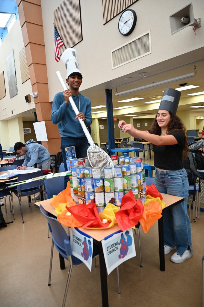 Cans in shape of pot with students stirring