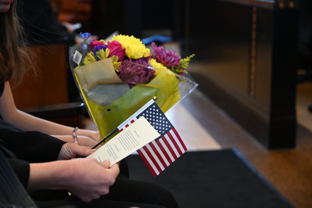 An image of a ceremony program, flowers and an American flag.