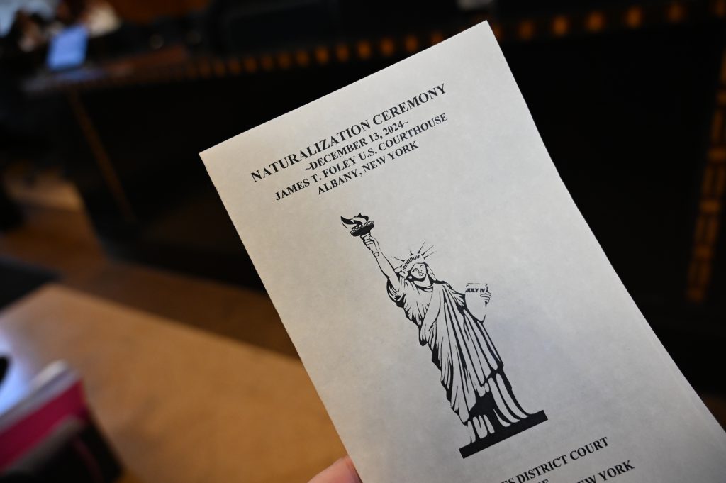 An image of a program that reads "Naturalization Ceremony, December 13, 2024"