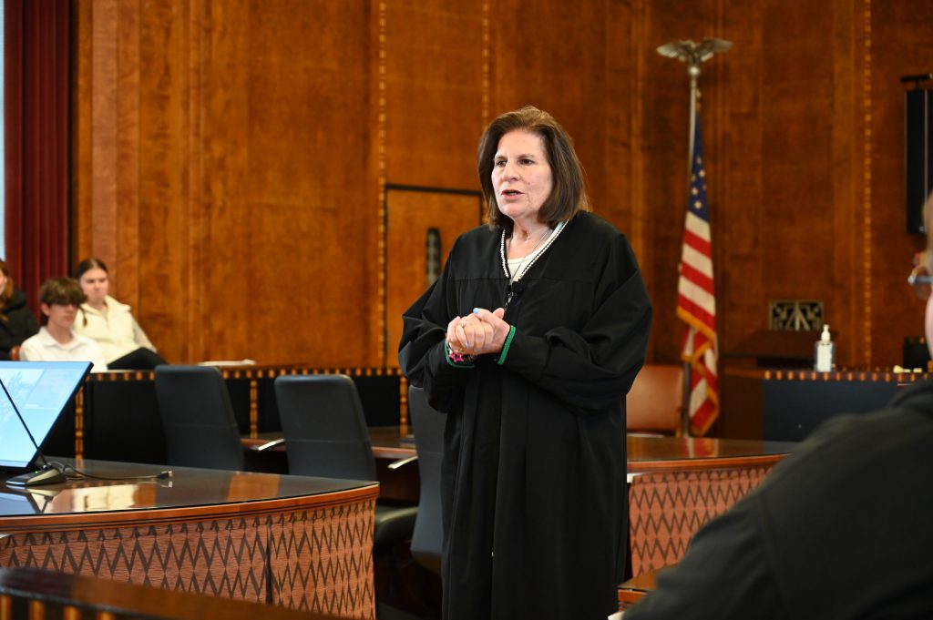 An image of a judge standing in front her courtroom.