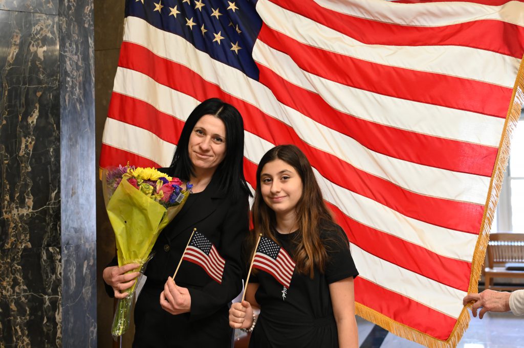 An image of a woman and her daughter posing in front of the American flag.