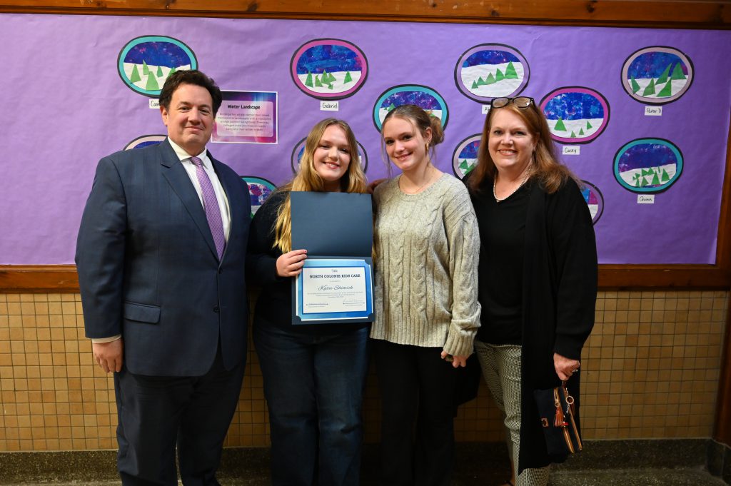 An image of a student and her family posing with a certificate.