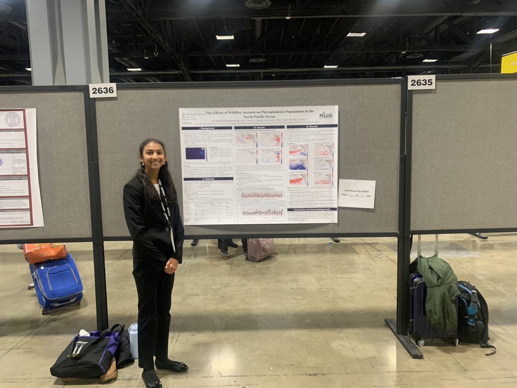 An image of a student standing in front of a posterboard of her presentation.