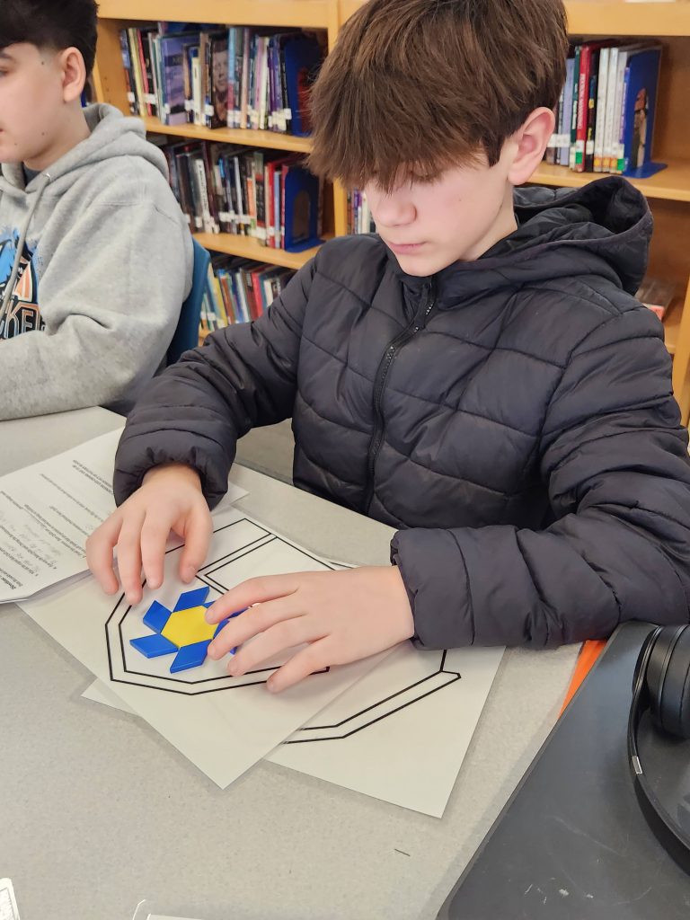 An image of a student creating a barn quilt using balsa blocks.