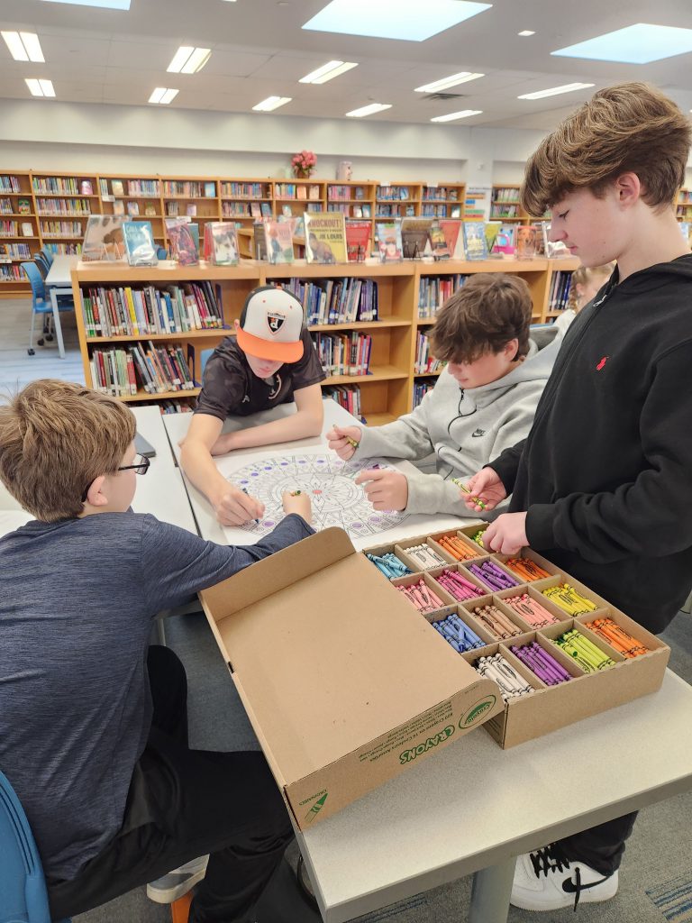 An image of four students around a table coloring a mandala.