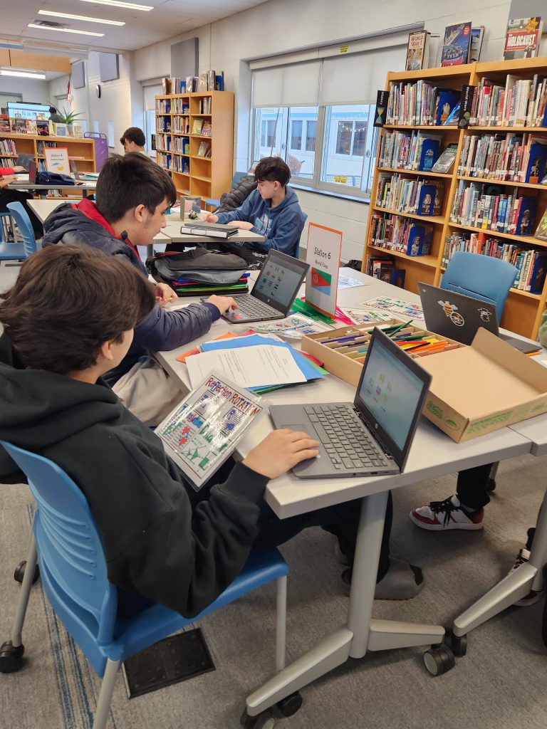 An image of students looking at world flags on their laptops.