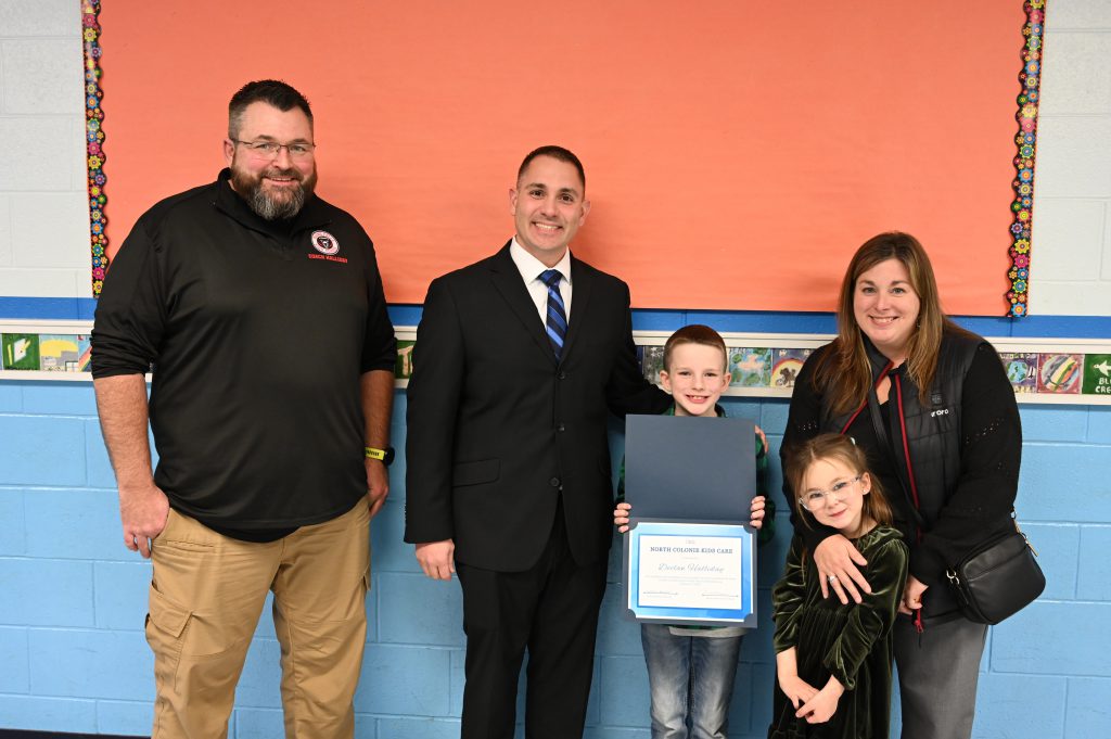 An image of a student holding a certificate surrounded by his family.