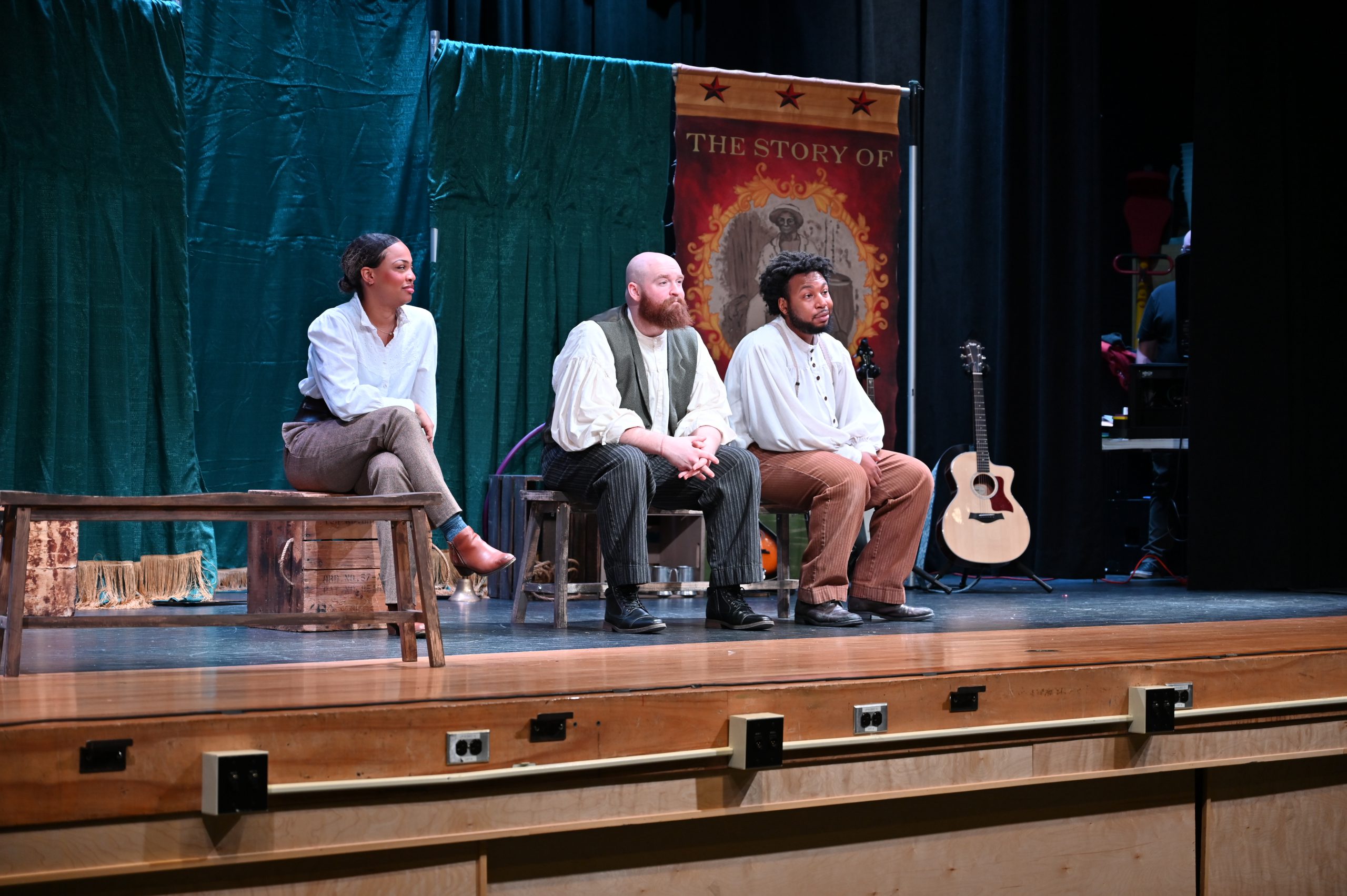 An image of three actors sitting on a stage.