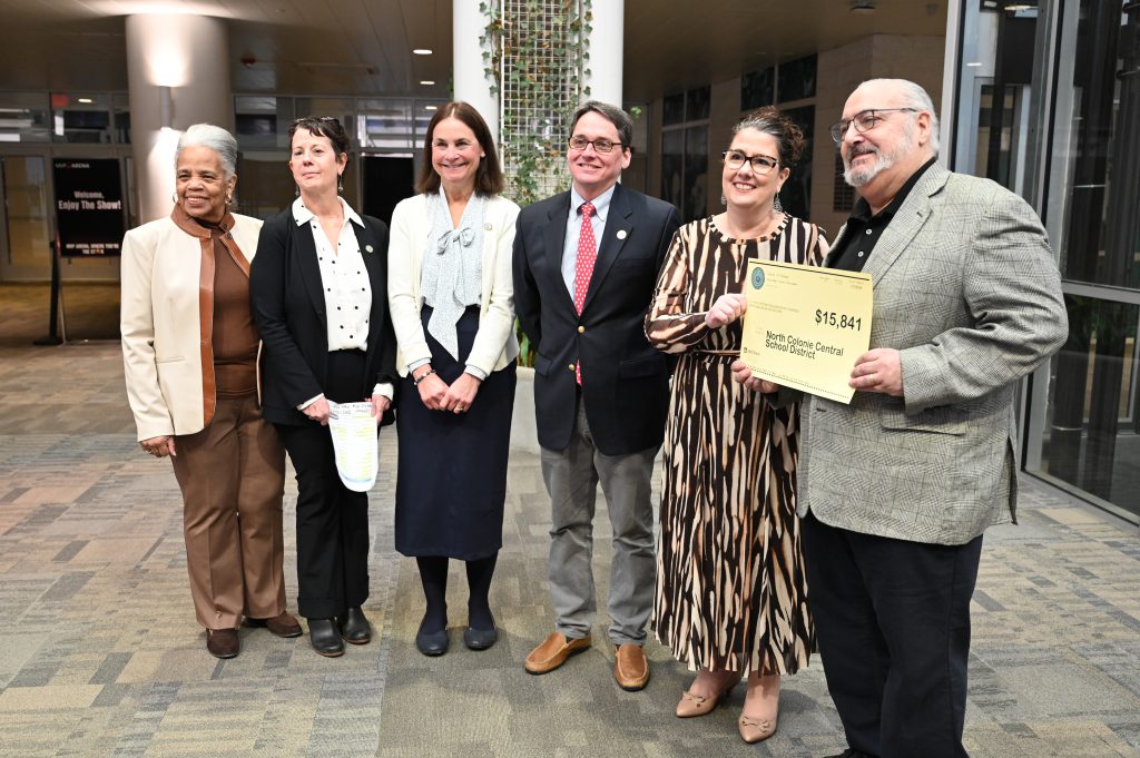 An image of six people standing and holding a grant check.