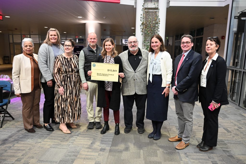 An image of nine people holding a check.