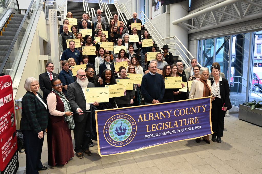 An image of dozens of people holding grant checks on a staircase.