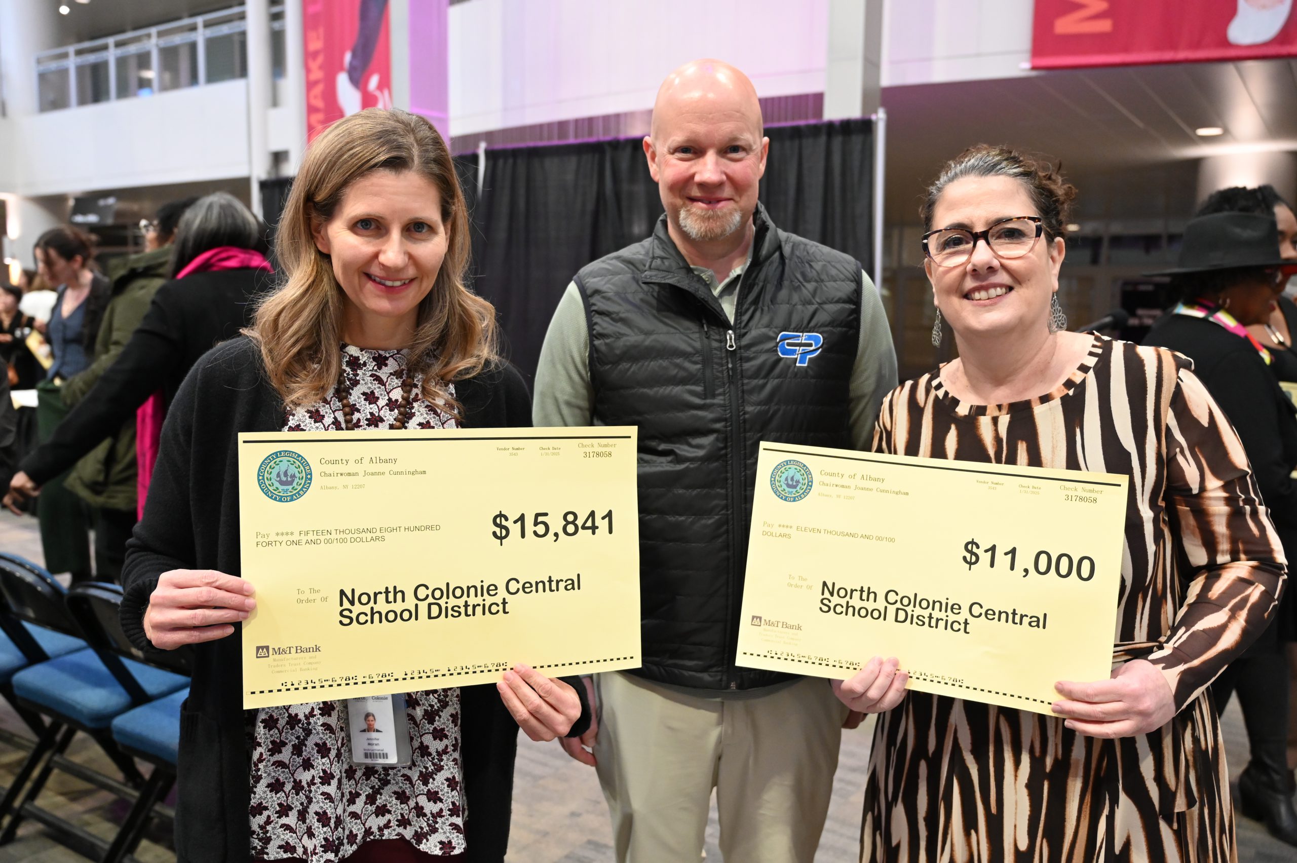 An image of three adults holding two grant checks.