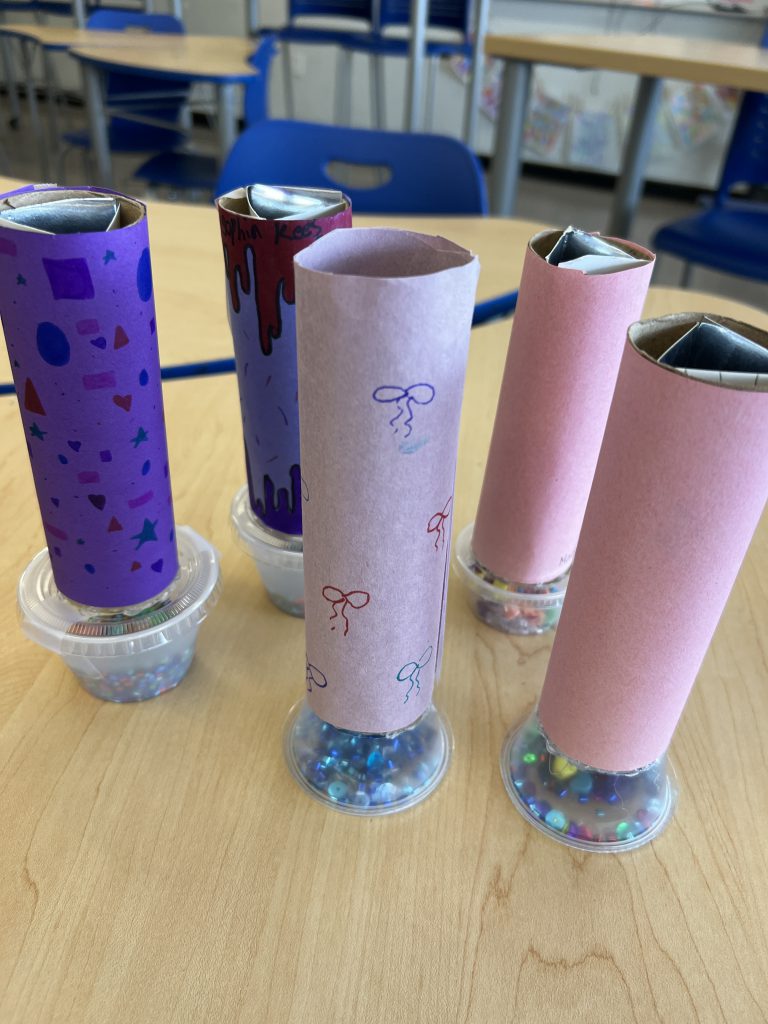 An image of five kaleidoscopes standing up on a table.