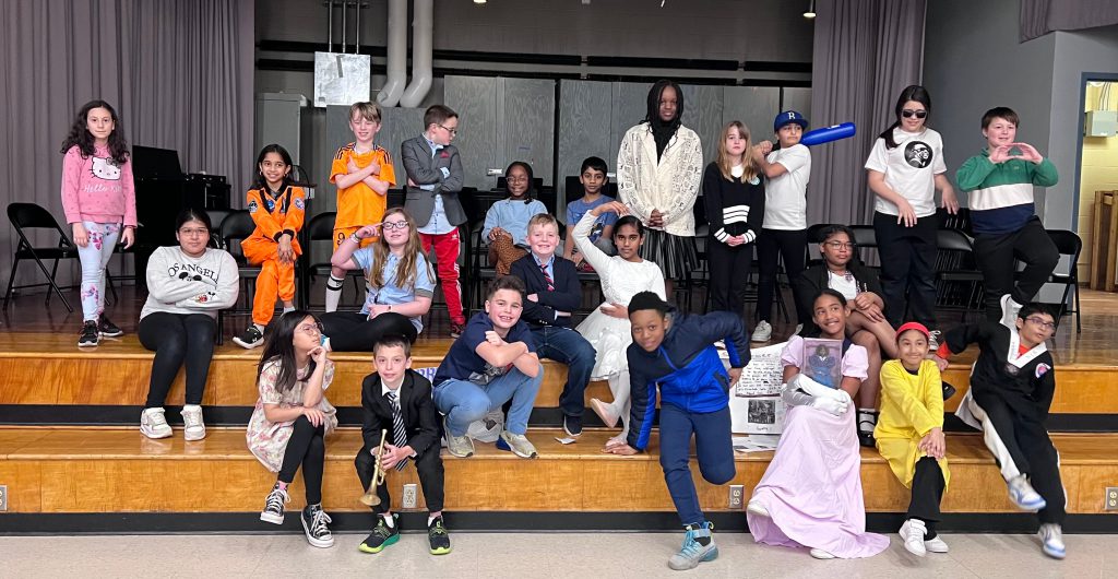 An image of a class of fourth graders, dressed up and posing on stage.