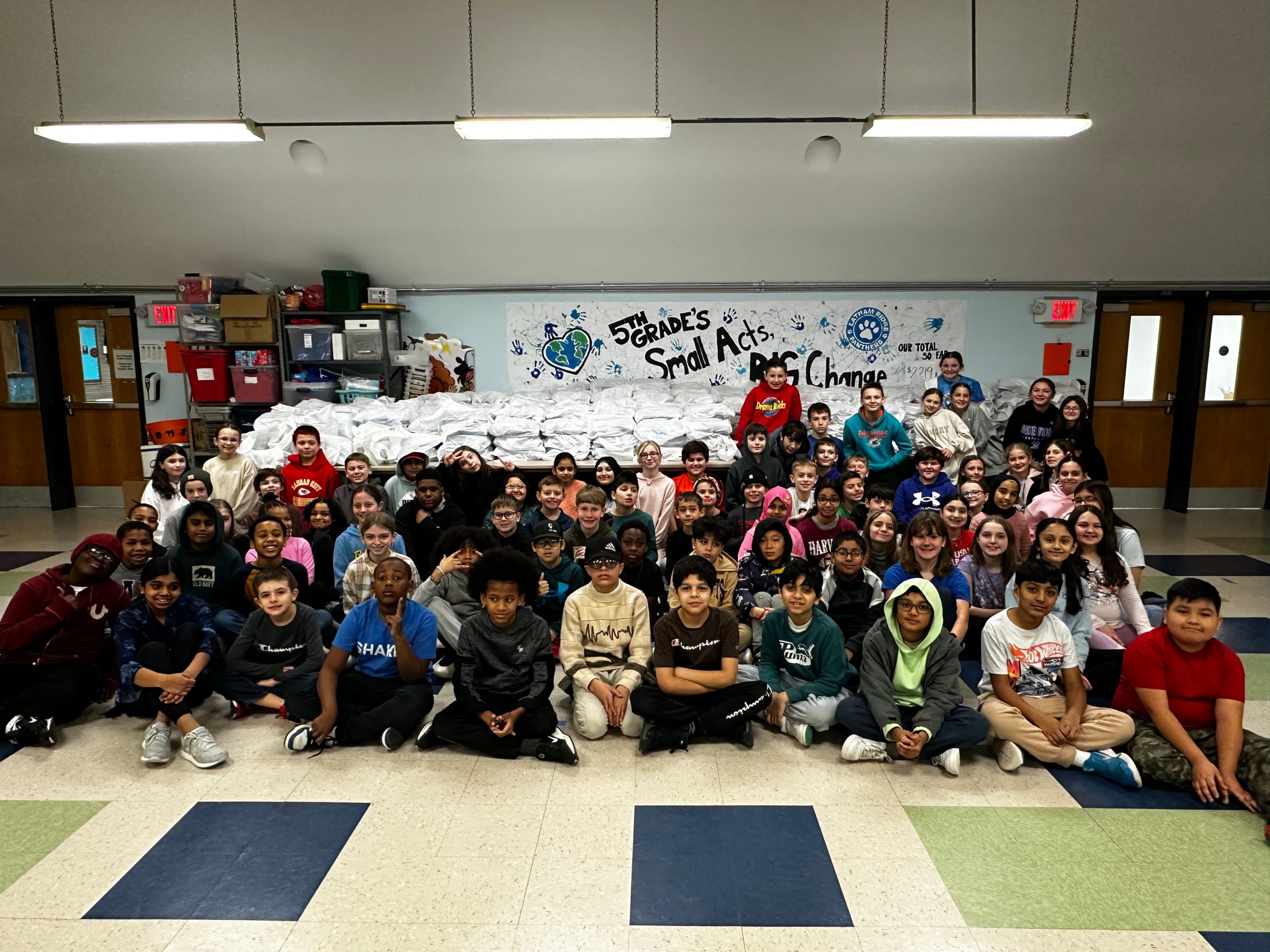 An image of a large group of students posing in front of birthday kits they put together to donate to the food bank.