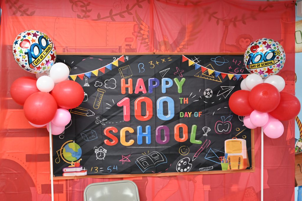 An image of balloons and a sign that says "Happy 100th Day of School."