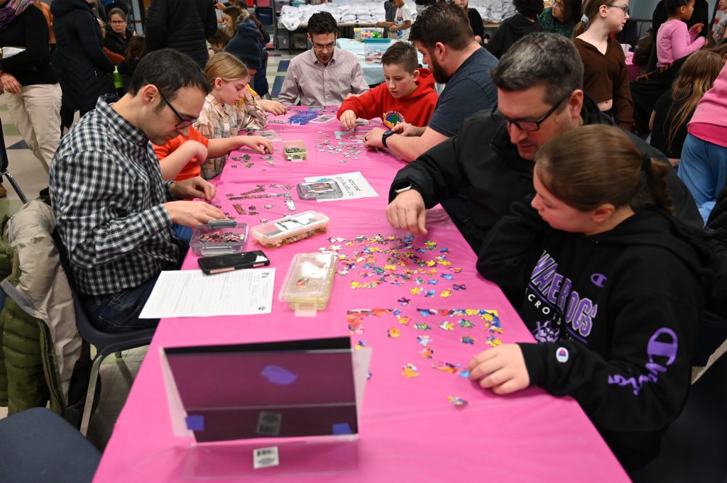 An image of adults and students at a table doing hands on activities.