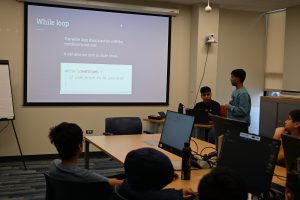 A group of students look at screen to learn java coding at the library