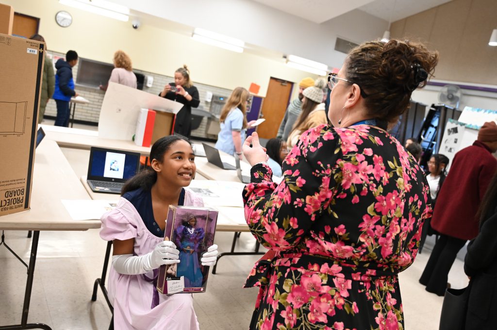 A student presents her presentation to an onlooking administrator.