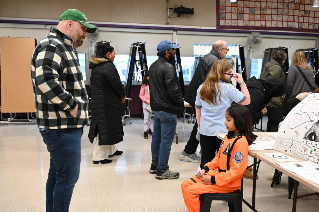 An image of a student dressed as an aerospace technologist presenting to an adult.