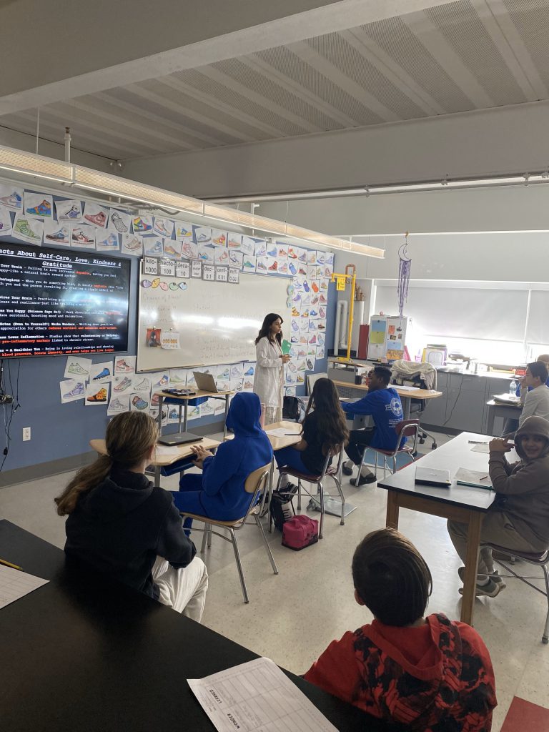 An image of a doctor standing at the front of a classroom speaking to students.