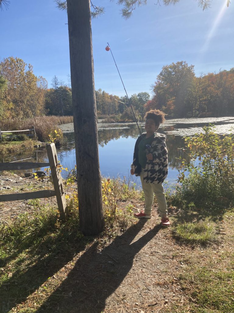 An image of a child holding a fishing pole by a body of water.