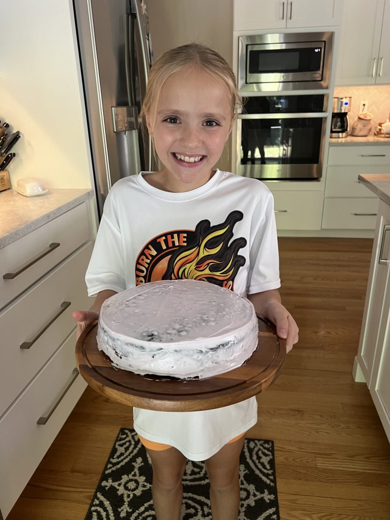 An image of a student showing off a freshly baked cake.