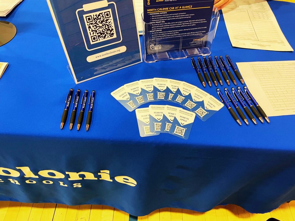 An image of a table with North Colonie Central School District pens and promotional cards on it.