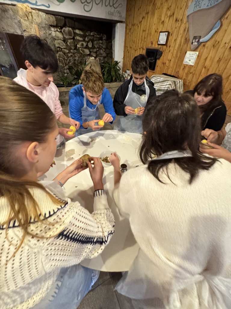 An image of students standing around a table and using their hands to make pasta.